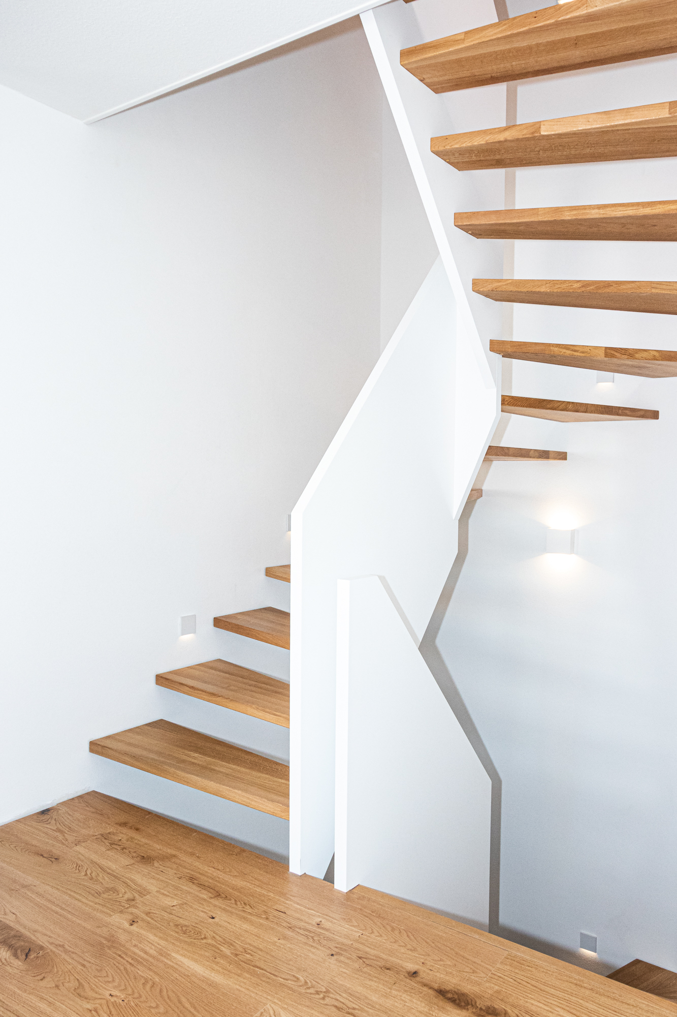 Minimalistisches Treppendesign mit offenen Stufen und durchgehenden, brüstungshohen Wangen